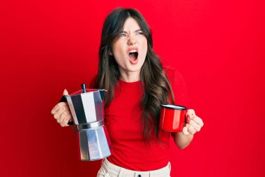 Genç, güzel, beyaz bir kız İtalyan kahvesi içiyor öfkeli ve öfkeli çığlıklar atıyor öfkeyle bağırıyor. öfke ve agresif konsept. 