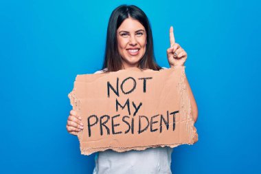 Fikir ayrılığı yaşayan genç güzel bir kadın, elinde afiş tutarken başkanlık mesajım olmadan bir fikir veya soru işareti ile gülümsüyor, bir numara: