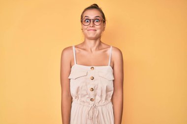 Yazlık elbiseler giyen güzel beyaz kadın komik yüzlü yanak şişiriyor. Havayla şişmiş ağız, çılgın bir ifade.. 