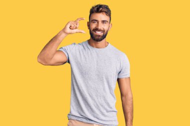 Gündelik kıyafetler giyen, gülümseyen, kendine güvenen, el hareketi yapan, parmaklarıyla işaret yapan ve kameraya bakan genç İspanyol bir adam. ölçüm kavramı. 