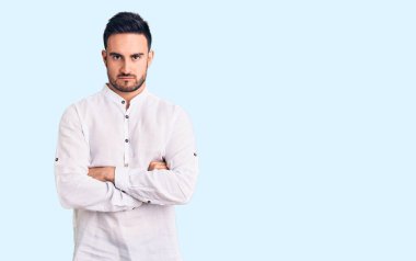 Gündelik kıyafetler giyen, kuşkucu ve gergin genç yakışıklı bir adam. Yüzünde çapraz kollarla onaylamayan bir ifade var. negatif kişi. 