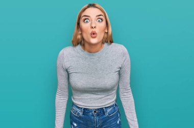 Gündelik giysiler giyen genç beyaz bir kadın. Şaşırmak için ağzı açık kalmış, korkmuş ve şaşkına dönmüş. 