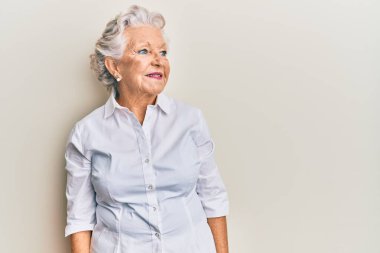 Kıdemli, gri saçlı, günlük kıyafetler giyen, rahat bir görünüm takınan, doğal yüzlü ve kendine güvenen bir gülümseme takınan bir kadın.. 