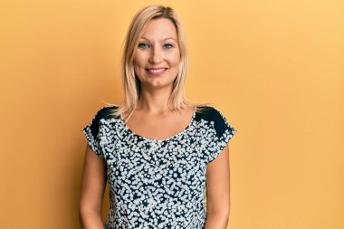 Orta yaşlı, beyaz, sıradan kıyafetler giyen mutlu ve havalı bir gülümsemesi olan bir kadın. şanslı kişi. 