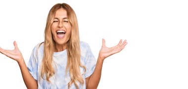 Kravat boyası tişörtü giyen güzel sarışın bir kadın başarının çılgınlığını kutluyor kolları havada ve gözleri kapalı heyecanla bağırıyor. Kazanan konsept 