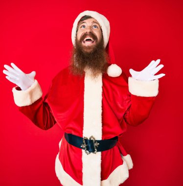 Uzun sakallı, yakışıklı, Noel Baba kostümü giyen, başarı için deli ve çılgın bir kutlama yapan, kolları havada ve gözleri kapalı, heyecanlı bir genç adam. Kazanan konsept 