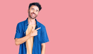 Yüzünde mutlu ve doğal bir ifade olan, elleri ve parmaklarıyla işaret eden, güler yüzlü, gündelik kıyafetler giyen genç İspanyol adam. 