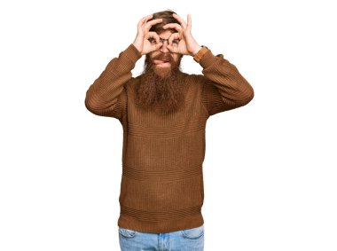 Genç İrlandalı kızıl elbiseli ve gözlüklü bir adam dürbün gibi jest yapıyor. Dürbün gibi dilini çıkarıyor, gözler parmaklarından bakıyor. çılgın ifade. 