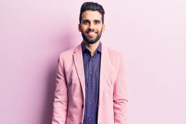 Sakallı, zarif ceketli, yüzünde mutlu ve havalı bir gülümseme olan yakışıklı bir genç. şanslı kişi. 