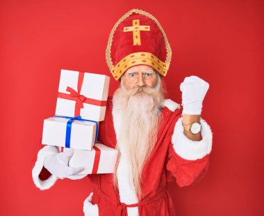 Gri saçlı, uzun sakallı, Aziz Nicholas kostümü giymiş yaşlı bir adam. Elinde hediyeler var. Sinirli ve sinirli bir şekilde bağırıyor. 