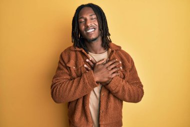 Saçları kahverengi retro ceket giyen, elleri göğsünde, gözleri kapalı ve yüzünde minnet ifadesi olan Afro-Amerikan bir adam. sağlık kavramı. 