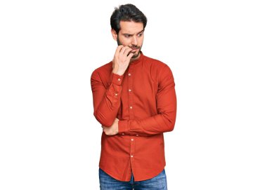 Günlük kıyafetler giyen genç İspanyol adam gergin ve gergin görünüyor. Ağzı tırnak yiyen eller. anksiyete. 