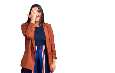 Genç, güzel, esmer, zarif kıyafetler giyen bir gözünü eliyle kapatan, yüzünde kendine güvenen bir gülümseme ve sürpriz bir duygu olan bir kadın.. 