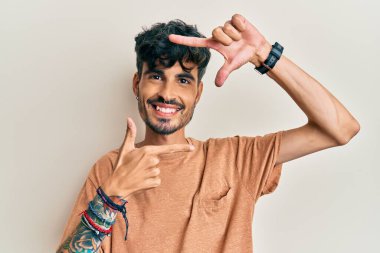 Gündelik kıyafetler giyen, gülümseyen, elleri ve parmakları gülen yüzlü, çerçeveli bir İspanyol. yaratıcılık ve fotoğrafçılık kavramı. 