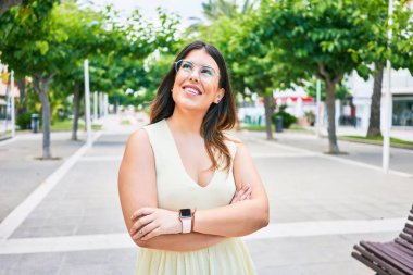 Kolları bağlı mutlu gülümseyen genç ve güzel bir kadın. Yüzünde tebessümle kasaba caddesinde yürürken yan tarafa bakıyor..