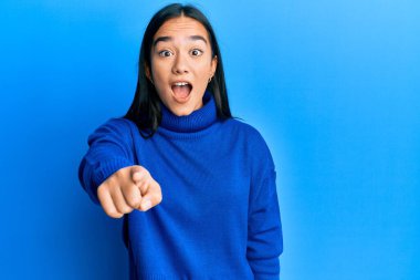 Sıradan bir süveter giyen genç Asyalı kadın kameraya kızgın ve sinirli bir şekilde seni işaret ediyor. 