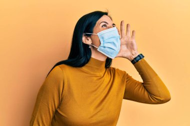 Tıbbi maske takan genç beyaz bir kadın el ele verip bağırıyor ve bağırıyordu. iletişim konsepti. 