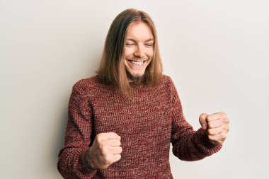 Uzun saçlı, sıradan bir kazak giyen yakışıklı beyaz adam kolları havada ve gözleri kapalı bir şekilde başarıyı kutluyor ve şaşırıyor. 