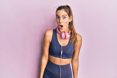 Spor kıyafetleri giyen ve kulaklık takan genç ve güzel bir kadın. Şaşırmış ve korkmuş bir ifade, korku ve heyecanlı bir yüz ifadesiyle.. 