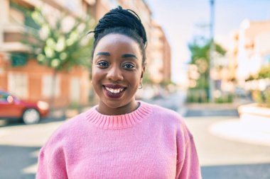 Genç Afrikalı Amerikalı kadın gülümseyerek şehirde mutlu mesut yürüyor..