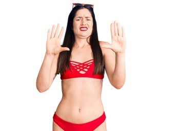 Bikini giyen güzel beyaz bir kadın korku ifadesinden korkuyor ve dehşete düşüyor. El hareketlerini bırak, şok içinde bağır. panik konsepti. 