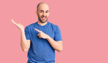 Gündelik tişört giyen genç yakışıklı adam kameraya hayret ediyor ve gülümsüyor.. 