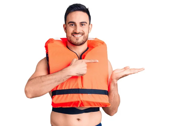Young Handsome Man Wearing Lifejacket Amazed Smiling Camera While Presenting — Stock Photo, Image