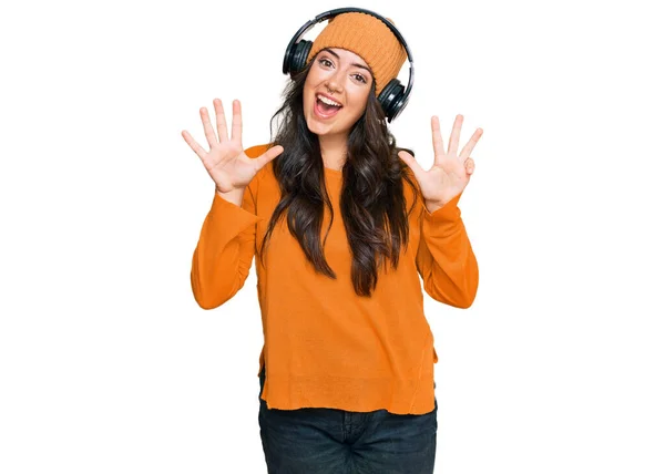 美しいブルネット若いです女性はヘッドフォンを使用して音楽を聞いて表示し 指数9で指摘しながら 自信と幸せ笑みを浮かべて — ストック写真