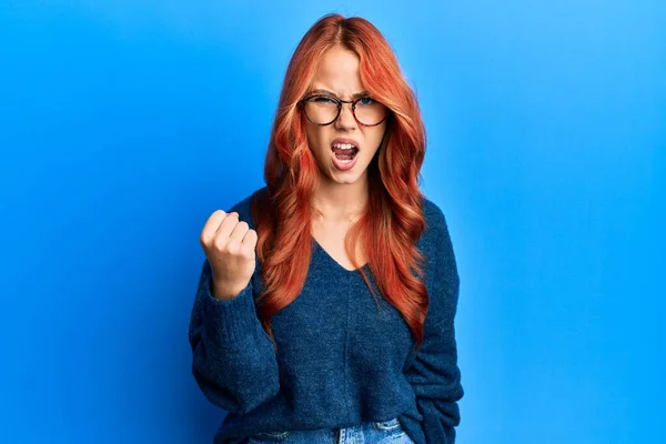 Ung Smuk Rødhåret Kvinde Iført Afslappet Sweater Briller Blå Baggrund - Stock-foto