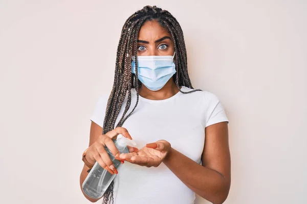 Νεαρή Αφροαμερικανή Γυναίκα Κοτσίδες Φορώντας Ιατρική Μάσκα Χρησιμοποιώντας Απολυμαντικό Χεριών — Φωτογραφία Αρχείου