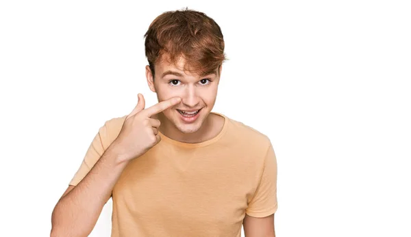 若い白人男性の顔や鼻に手指で指してカジュアルな服を着て 陽気な笑顔 美の概念 — ストック写真