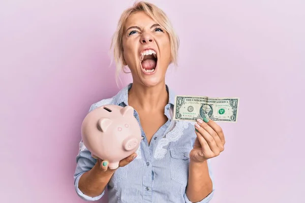 Young Blonde Girl Holding Dollar Piggy Bank Angry Mad Screaming — Foto Stock