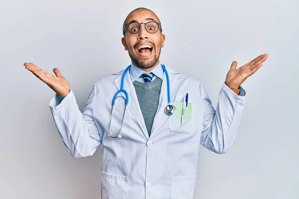 医者の制服と聴診器を着たヒスパニック系の成人男性は狂気を祝い 腕を上げ 興奮して叫んで目を開けて成功に驚いています 勝者のコンセプト — ストック写真