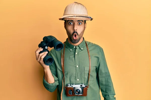 Giovane Uomo Ispanico Indossa Cappello Esploratore Guardando Attraverso Binocoli Spaventato — Foto Stock