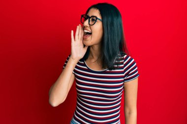 Güzel Asyalı genç bir kadın, günlük kıyafetler ve gözlük takıyor, bağırıyor ve ağızları açık bağırıyor. iletişim konsepti. 