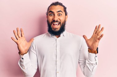 Genç Arap adam gündelik giysiler giyip çılgınlığı kutluyor ve başarıya hayret ediyor kolları açık ve gözleri açık heyecanla haykırıyor. Kazanan konsept 