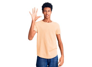 Genç Afro-Amerikalı günlük kıyafetler giymiş beş numarayı gösterip işaret ederken kendinden emin ve mutlu bir şekilde gülümsüyor.. 