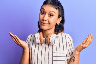 Kulaklık takıp müzik dinleyen genç bir kadın. Kolları açık ve kafası karışık. Hiç bir fikrim yok.. 