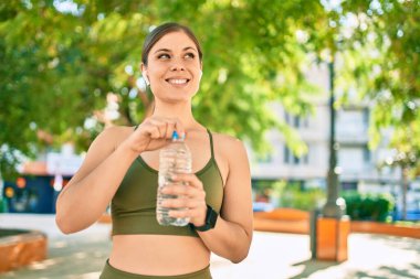Genç sarışın sporcu şehirde bir şişe su içerek egzersiz yapıyor..