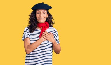 Orta yaşlı, güzel bir kadın, Fransız beresi ve atkısı takmış, elleri göğsünde, gözleri kapalı ve yüzünde minnet dolu bir jest ile gülümsüyor. sağlık kavramı. 