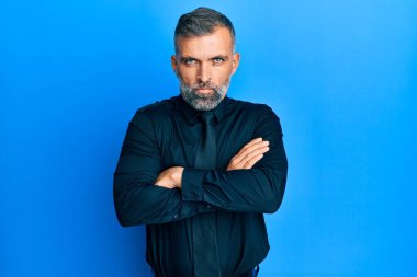 İş gömleği giyen, kravat takan, kuşkucu ve gergin orta yaşlı yakışıklı bir adam. Yüzünde çapraz kollarla onaylamayan bir ifade var. negatif kişi. 