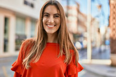 Genç İspanyol kadın gülümseyerek şehirde mutlu mesut dikiliyor..