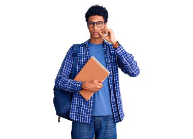 Sırt çantalı, ağzı kitap gibi kapalı ve dudakları parmakları olan Afro-Amerikan genç bir adam. gizli ve sessiz, tabu konuşması 