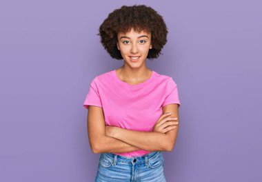 Gündelik kıyafetler giyen, kollarını kavuşturup kameraya gülümseyen genç İspanyol kız. pozitif kişi. 