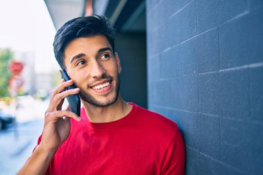 Genç Latin adam gülümsüyor. Şehirdeki akıllı telefondan konuşuyor..