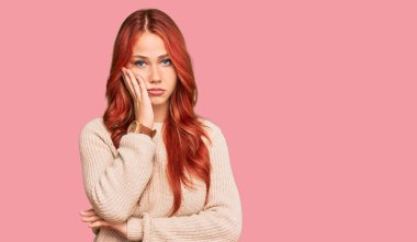 Kış süveteri giyen genç kızıl saçlı kadın kollarını kavuşturup depresyondan sıkılmış ve yorgun göründüğünü düşünüyor.. 