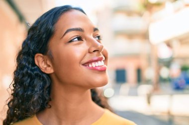 Genç Afrikalı Amerikalı kız gülümseyerek şehirde mutlu bir şekilde yürüyor..