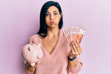 Elinde Norveç kronu banknotları tutan beyaz bir kadın ve komik suratlı bir domuz yavrusu. Ağzı havayla şişer, havayı yakalar.. 