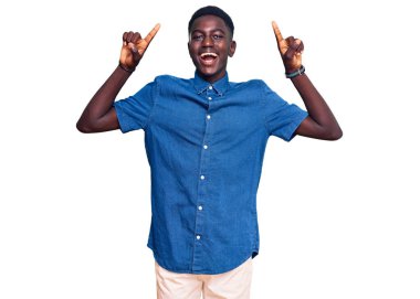 Gündelik giysiler giyen genç Afrikalı Amerikalı adam şaşkın şaşkın ve şaşırmış bir şekilde parmaklarıyla işaret ediyor ve kollarını kaldırıyordu.. 