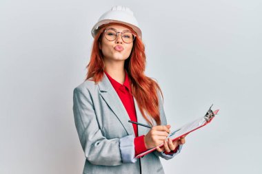 Genç, kızıl saçlı, mimar şapkalı, kameraya bakıp öpüşen güzel ve seksi bir kadın. aşk ifadesi. 